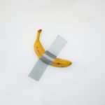 taped yellow banana on white surface